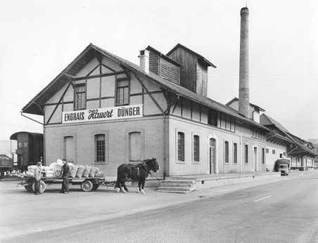Düngerfabrik in Suberg um 1963. Beladenes Pferdegespann steht vor dem Produktionsgebäude. Mit Hans-Jürg Hauert (2. v. l.).
(Scan: 3.03_1963_003, Firmen- und Familienarchiv Hauert, Grossaffoltern)